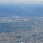 aerial view of Vancouver with blue mountains in the background and Fraser River in front centre